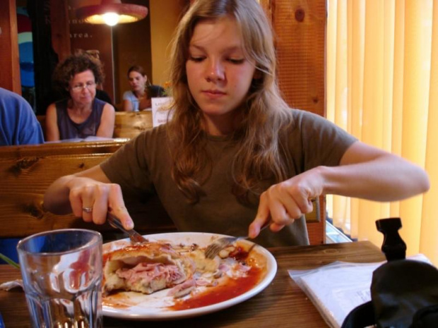 Agata wcina wielką pizzę calzzone.